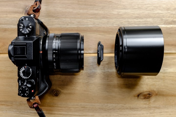 A view down on a black X-T10 with the 60mm f2 mounted with the hood and lens cap detached and placed in front of it.